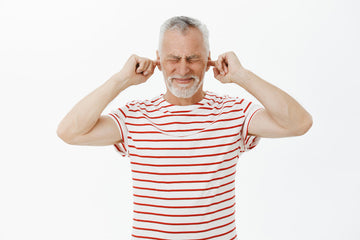 older gentleman covering his ears in pain due to tinnitus