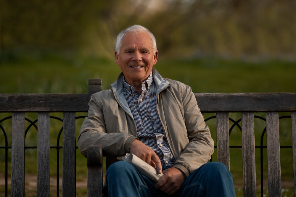 Happy older gentleman facing camera while sitting on a park bench