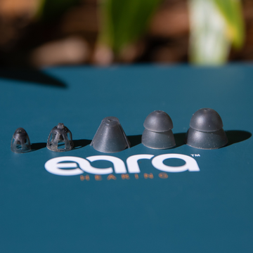 Eara Hearing earbud tips on a blue surface with 'Eara Hearing' branding.